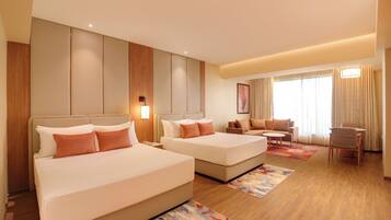 A hotel room with two beds, a sofa, a small table, and a chair.
