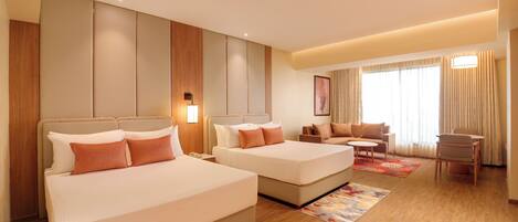 A hotel room with two beds, a sofa, a small table, and a chair.