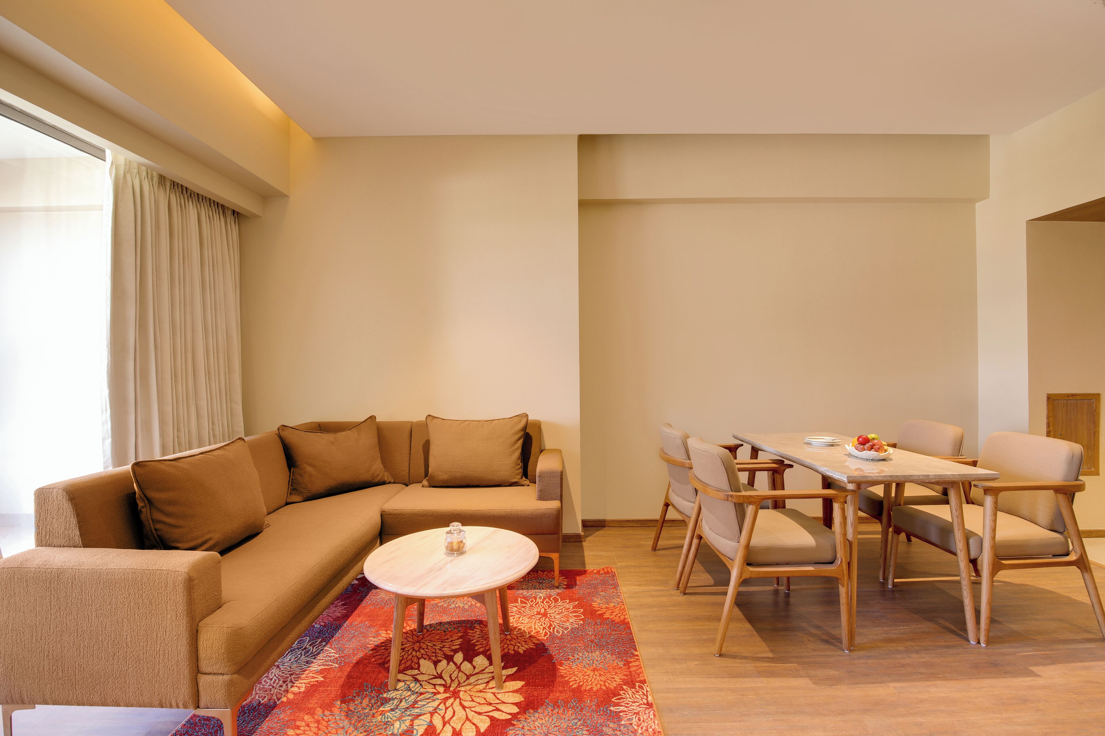 A modern living room with a sofa, a round coffee table, and a dining area with a table and chairs.