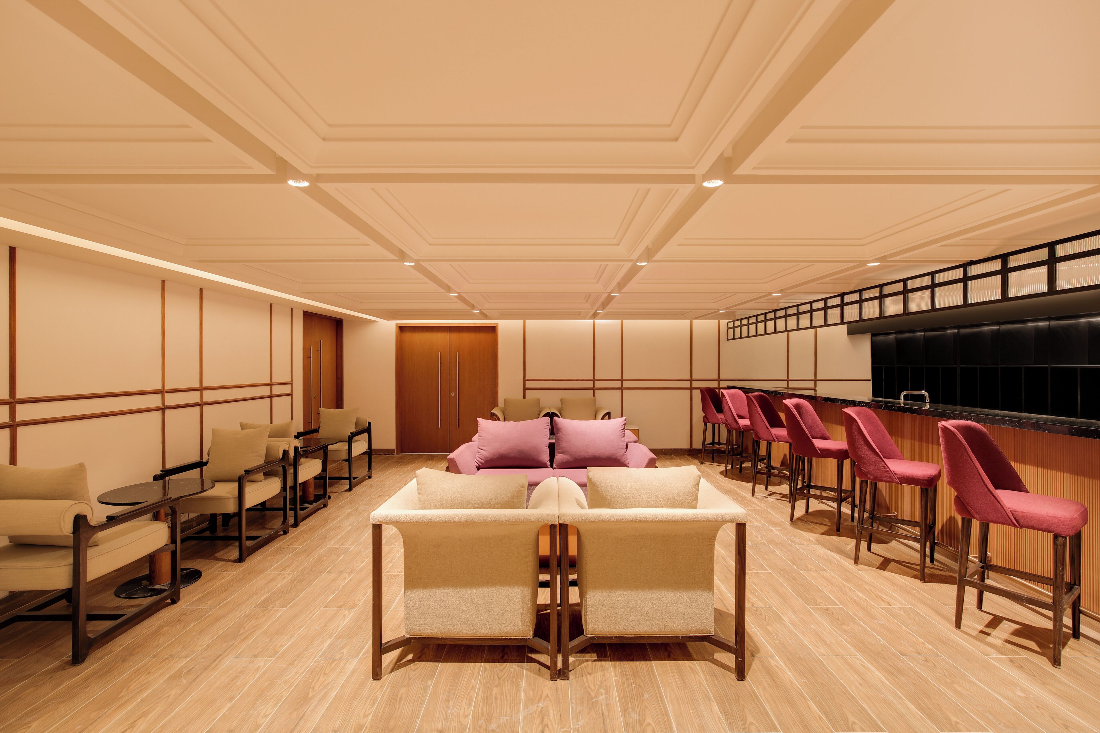 A modern hotel lobby with a seating area, a bar, and a reception desk.