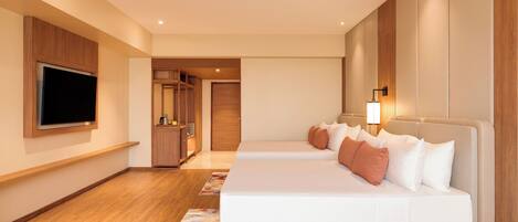 A modern hotel room with a large bed, a flat-screen TV mounted on the wall, a wardrobe, and a small desk area.