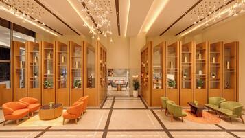 A spacious lobby with modern furniture, a central seating area, and a view into the dining area.
