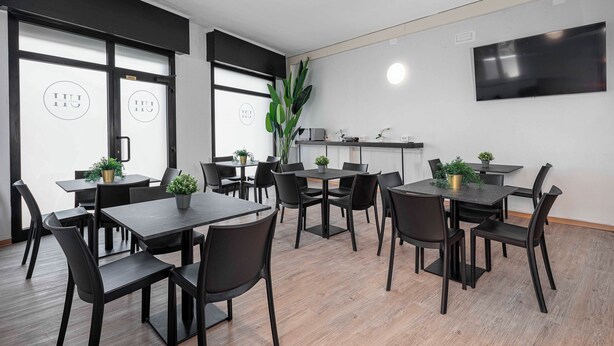 A modern meeting room with black furniture, large windows, and a flat-screen TV on the wall. - Urban Hotel (Cesena)