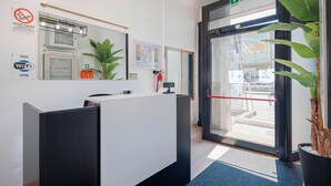 A reception area with a desk, a fire extinguisher, a WiFi sign, and a plant. - Urban Hotel (Cesena)