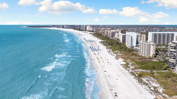 A coastal cityscape with a wide beach, high-rise buildings, and a clear sky.