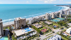 A coastal resort with high-rise buildings, a beach, and a parking area.