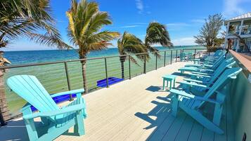 Eine Terrasse mit blauen Stühlen und Blick auf das Meer.