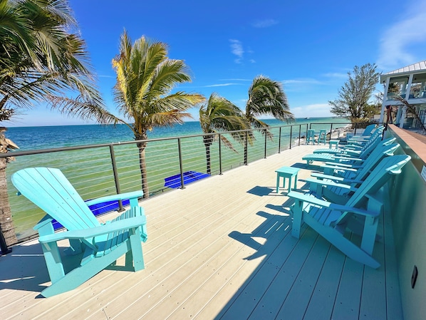 A deck with blue chairs and a view of the ocean. - The Rod and Reel Resort-Suite 1 (Anna Maria)
