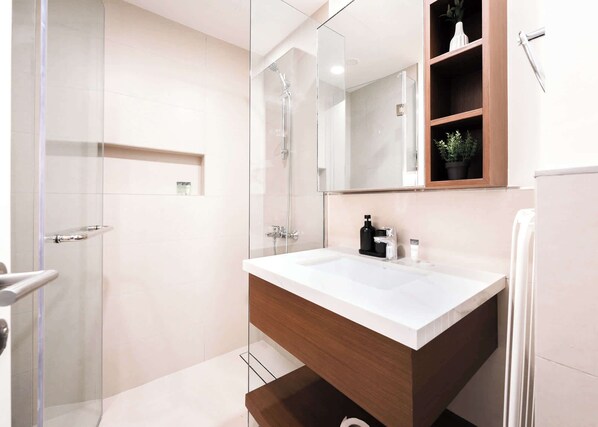 A modern bathroom with a glass-enclosed shower, a wooden vanity with a white sink, and a mirror above the vanity.