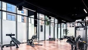Un gimnasio con equipo de ejercicio, amplias ventanas y suelo de madera.