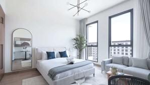 Una habitación de hotel moderna con una cama grande, un sofá, una mesa de comedor y un balcón con vistas a la ciudad.