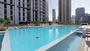 A swimming pool with lounge chairs and a view of tall residential buildings.