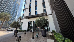 A modern building with a prominent entrance, large windows, and a sign indicating it is the Burj Crown hotel.