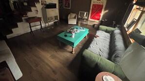 Un salon avec un canapé vert, une table basse de couleur turquoise et un escalier menant à un niveau supérieur.