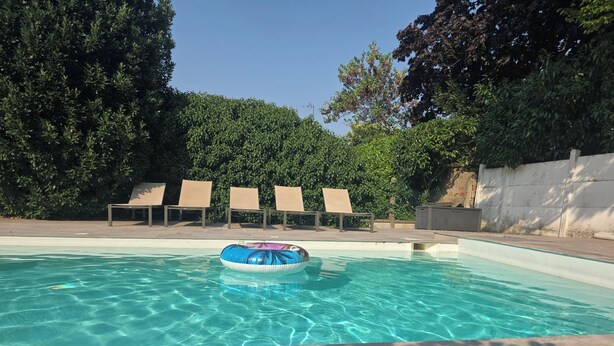 A swimming pool with clear water, surrounded by lounge chairs and greenery. - Le 46 Cosy, modern villa.  Between Paris, Disneyland and Parc Asterix (Villiers-sur-Marne)