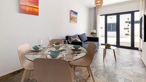 A dining area with a glass table, chairs, and bowls. There is a sofa and a small table with a plant in the background. - Casa Variza, tu refugio en Playa Blanca (Playa Blanca)