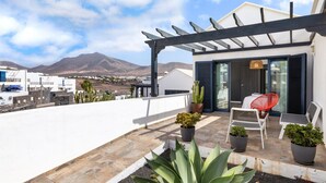 A rooftop terrace with a pergola, potted plants, and outdoor seating. - Casa Variza, tu refugio en Playa Blanca (Playa Blanca)