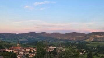 Un village avec un clocher d’église, entouré de collines douces et de verdure.