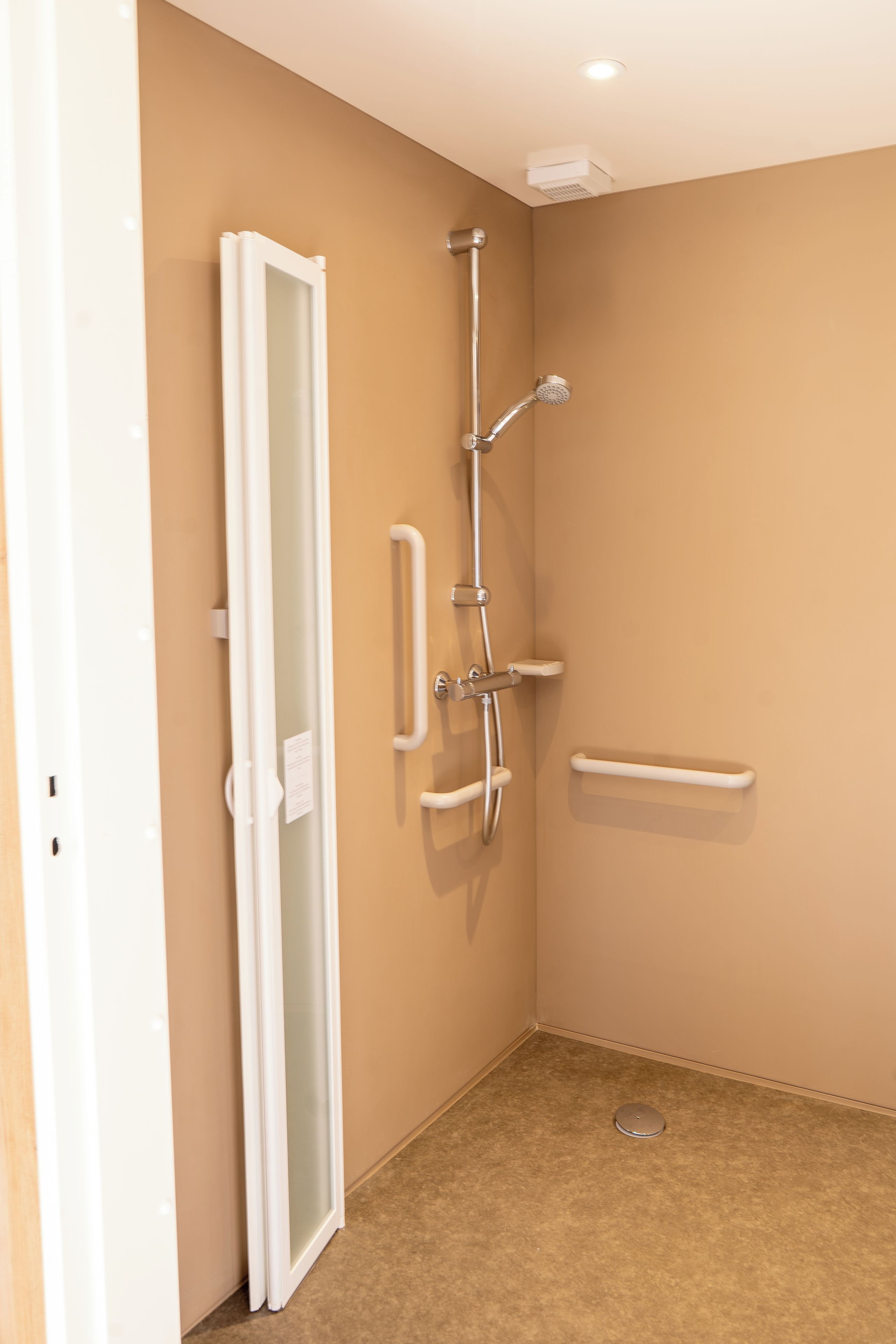 A bathroom with a shower, a toilet, and a glass door.