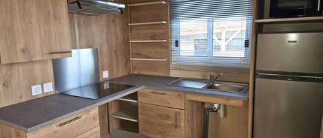 A compact kitchen with wooden cabinets, a stainless steel sink, and a built-in microwave.