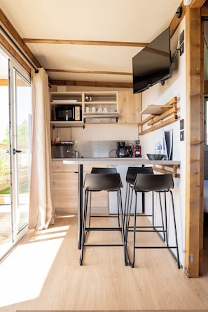 A modern kitchen with a built-in microwave, coffee maker, and a flat-screen TV mounted on the wall. - Tiny d'Monts (Brullioles)