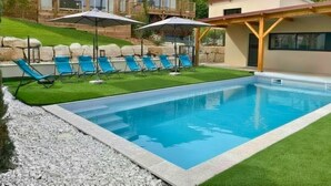 A swimming pool with blue water, surrounded by a grassy area and a wooden deck. - Tiny d'Monts (Brullioles)