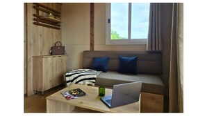 A modern living room with a sofa, a wooden cabinet, a laptop, and a magazine on a coffee table. - Tiny d'Monts (Brullioles)