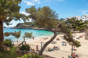 Une plage où l’on peut voir des gens bronzer et se baigner, entourée d’arbres et de bâtiments.