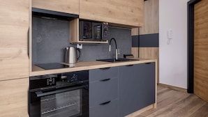 Eine moderne Küche mit Holzausstattung, einer integrierten Mikrowelle, einer Kaffeemaschine, einem Spülbecken und einem Geschirrspüler.
