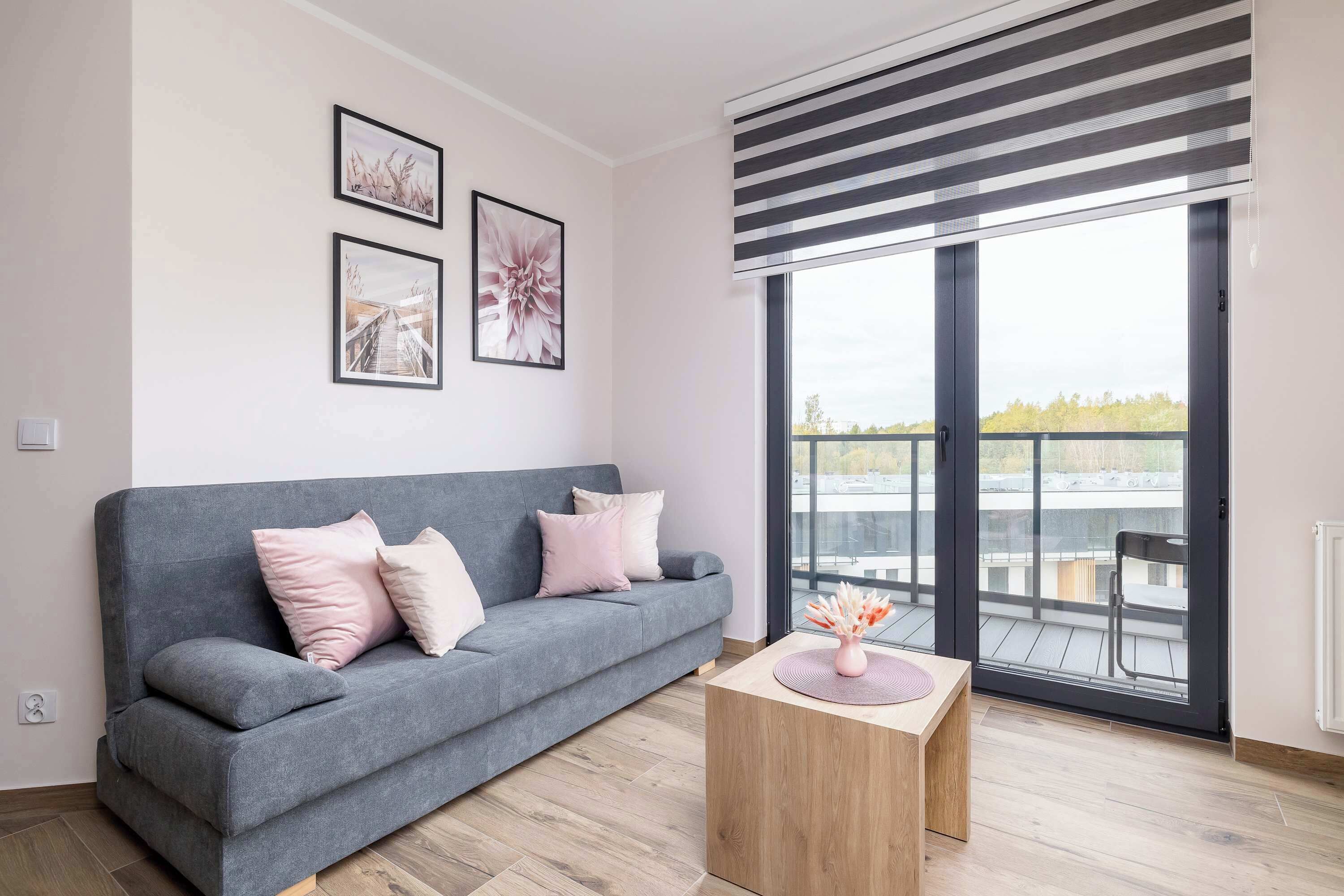 Ein modernes Wohnzimmer mit einem grauen Sofa, einem Holztisch und einem Balkon mit Blick.