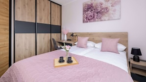Ein Schlafzimmer mit Bett, Nachttisch, Lampe und einem großen Blumenbild an der Wand.