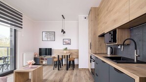 Eine moderne Küche mit Holzschränken, einem schwarzen Spülbecken und einem Essbereich mit Tisch und Stühlen.