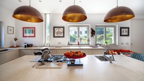 A modern kitchen with a central island, pendant lighting, and a view of the outdoors. - Pink Moon Villa. Private Pool. Close to the Beach. 10 guests. Luxury. (Fontane Bianche)