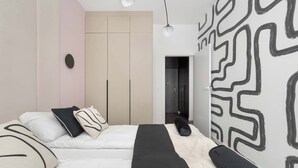 A modern bedroom with a bed, a wardrobe, and a wall with a geometric pattern.