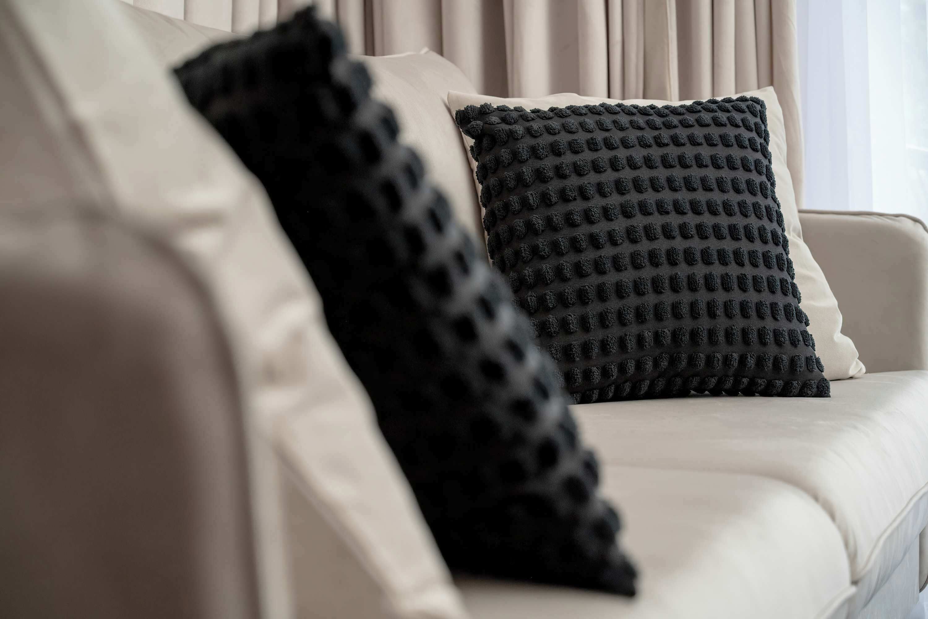 A sofa with two pillows, one with a textured pattern and the other plain.