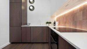 A modern kitchen with dark wood cabinets, a white countertop, and a built-in oven.