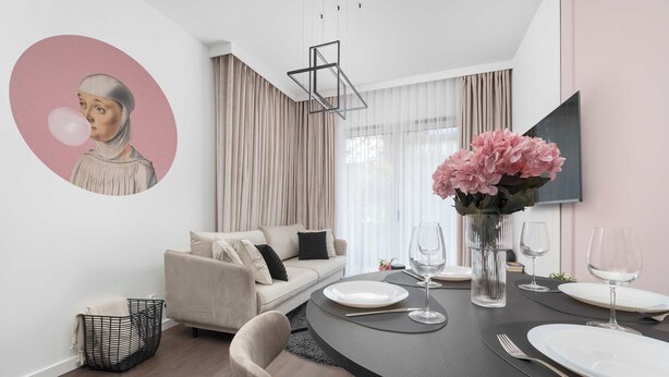 A modern dining area with a round table set for four, a sofa, and a large abstract painting on the wall.