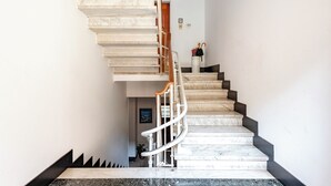 A marble staircase with a wooden handrail and black steps, leading to a landing with a door marked "2". - Spacious 2-bedroom flat near the beach (Rapallo)