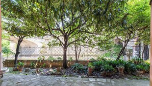 A courtyard with a large tree, potted plants, and a stone floor. - Spacious 2-bedroom flat near the beach (Rapallo)
