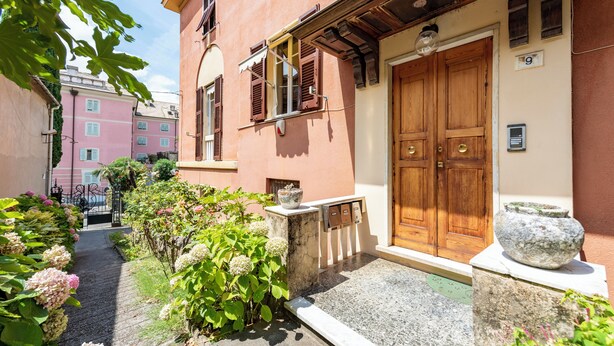 A narrow alley with a building featuring a large wooden door and a mailbox. - Spacious 2-bedroom flat near the beach (Rapallo)