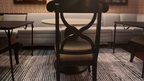 A room with a sofa, two armchairs, a dining table, and a chandelier.