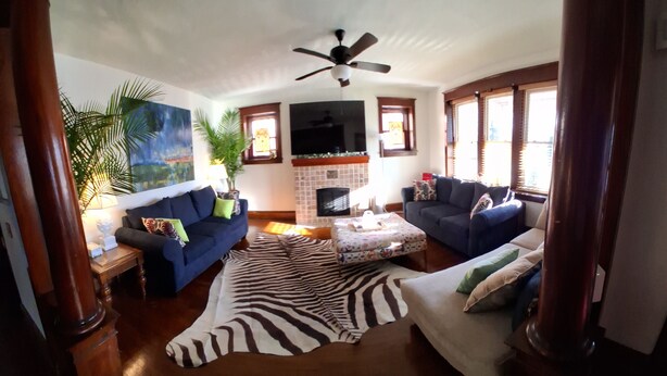 A living room with a fireplace, two sofas, a zebra rug, and a ceiling fan.