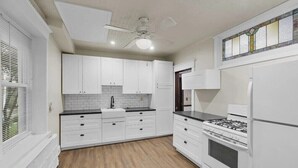 A kitchen with white cabinets, a black countertop, a stove, and a refrigerator.