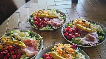A wooden table with five plates of assorted food items.