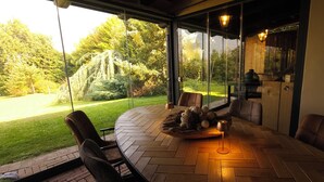 A modern outdoor dining area with a round table, chairs, and a view of a lush garden. - Villa Fonte  (Ferrere)
