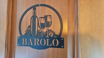 Un letrero de madera con un logotipo circular que muestra una botella de vino y copas, y la palabra 'BAROLO' debajo.