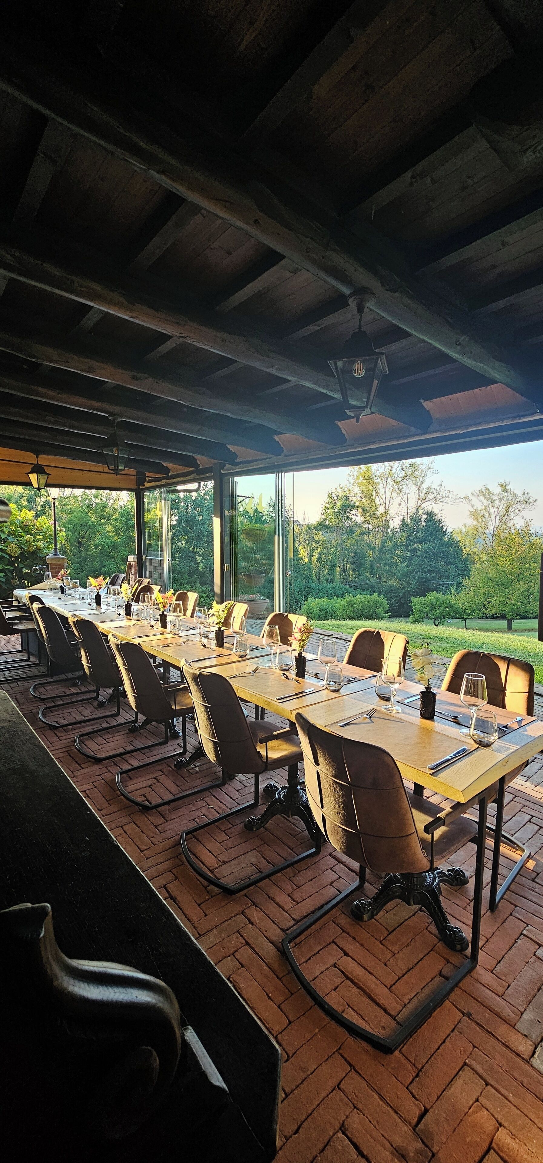 Un área de comedor al aire libre con suelo de ladrillo, mesas y sillas de madera.