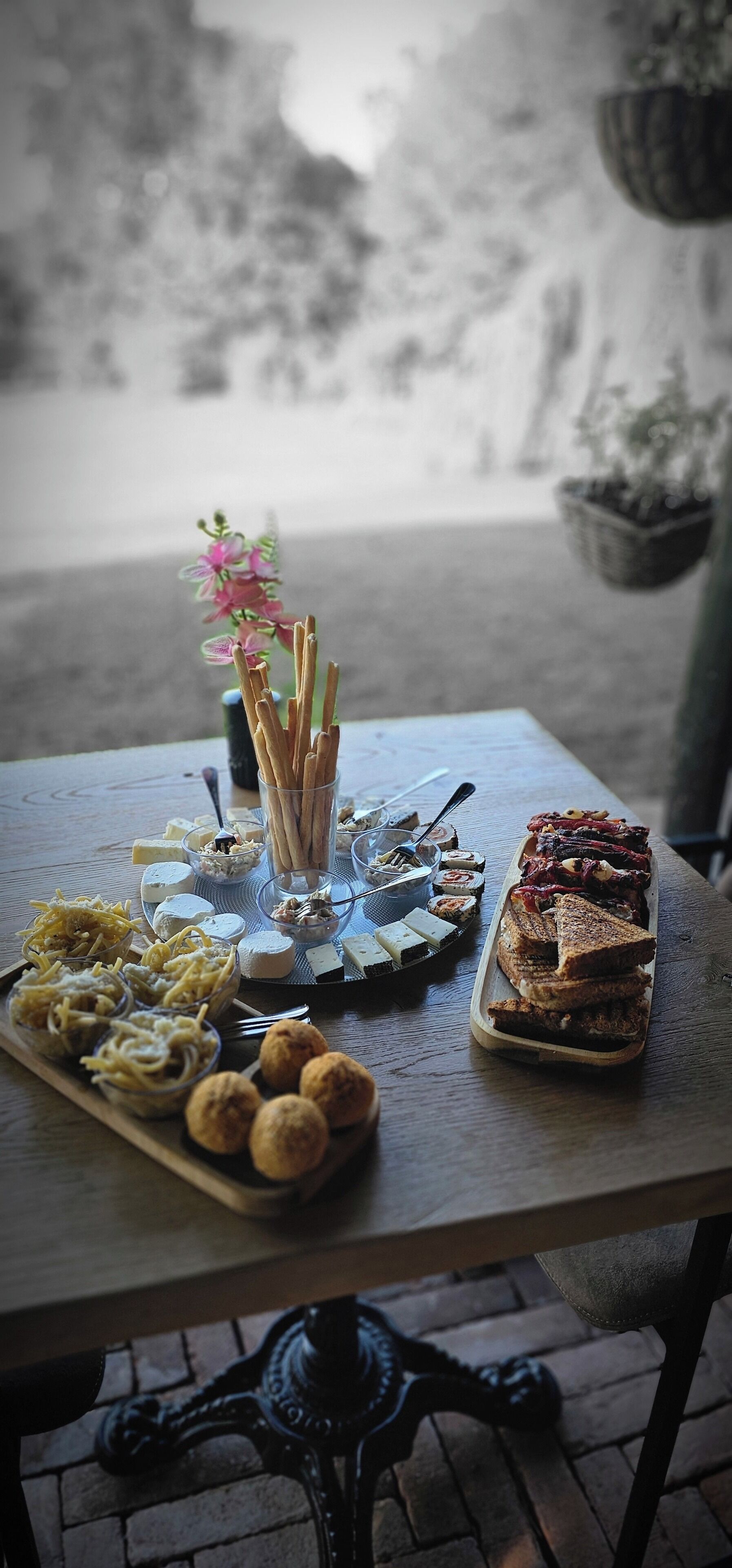 Un tavolo con diversi cibi, tra cui panini, dolci e un piccolo vaso con fiori.