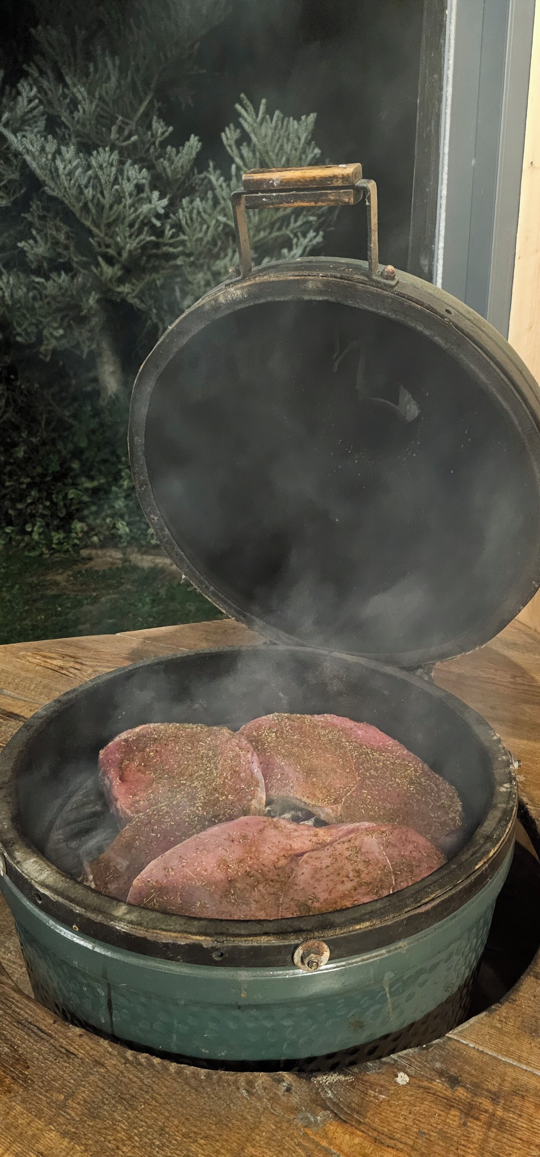 A portable grill with a lid open, revealing meat cooking inside.
