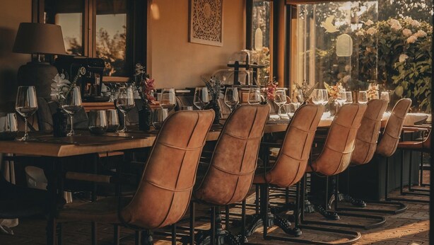 A dining area with a long table set for six, surrounded by leather chairs, with a view of greenery outside. - Villa Fonte  (Ferrere)
